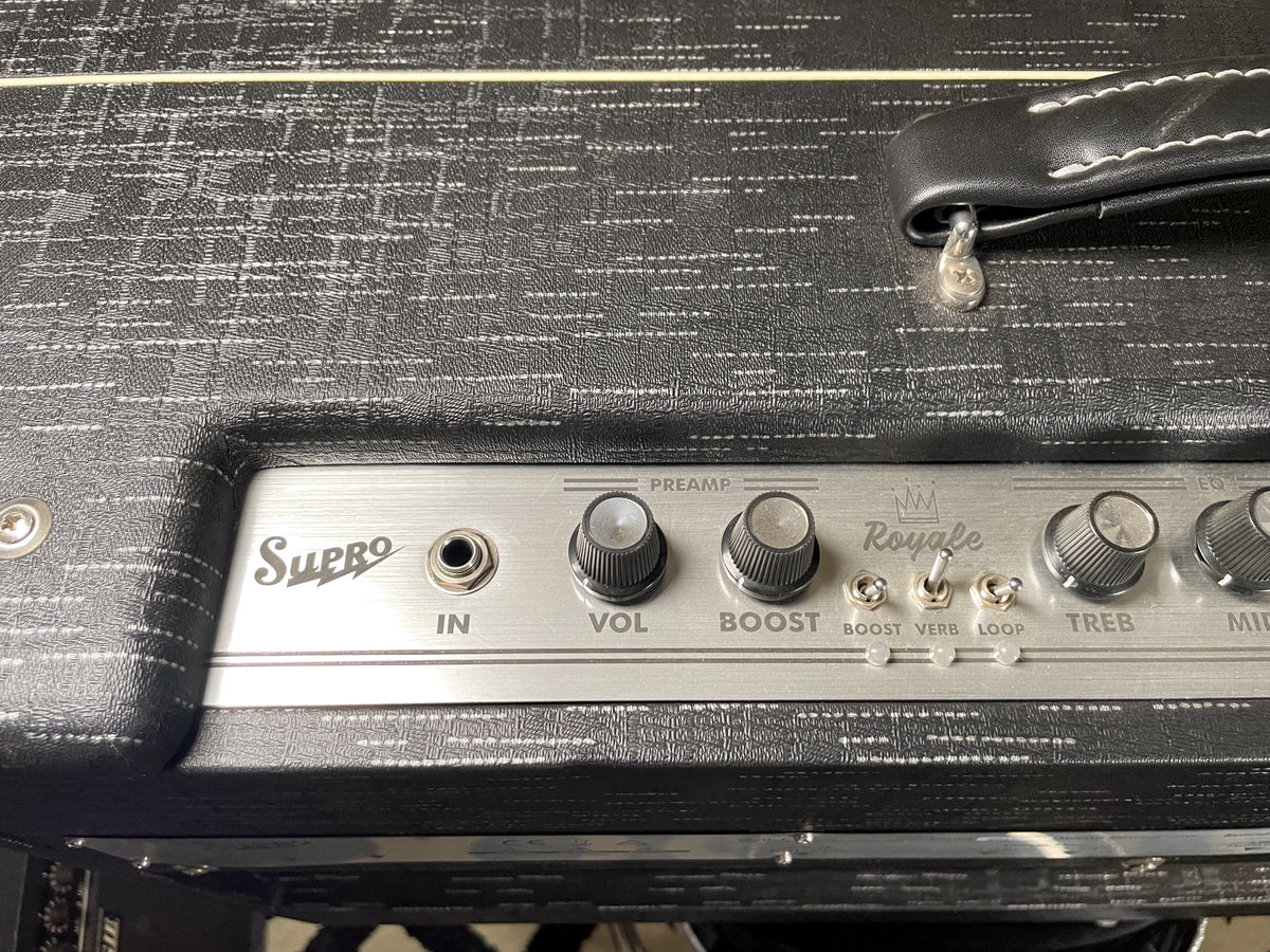 Close-up of the amp's black textured top, showing the silver control panel with input, five knobs, and three toggle switches.