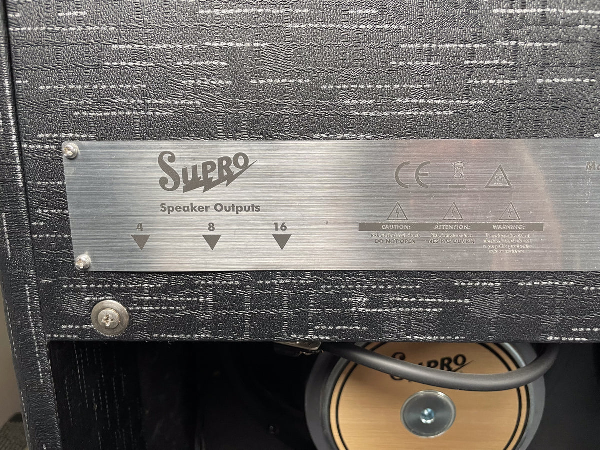 Close-up of the amp's textured black back panel, showing a brushed metal plate with "Speaker Outputs" and 4, 8, 16 ohm options.