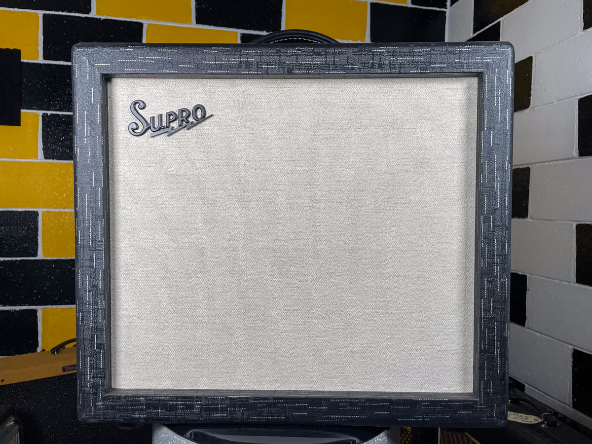 Front view of a dark grey combo amp with a textured, basketweave-like finish, light cream grille cloth, and a silver script logo.