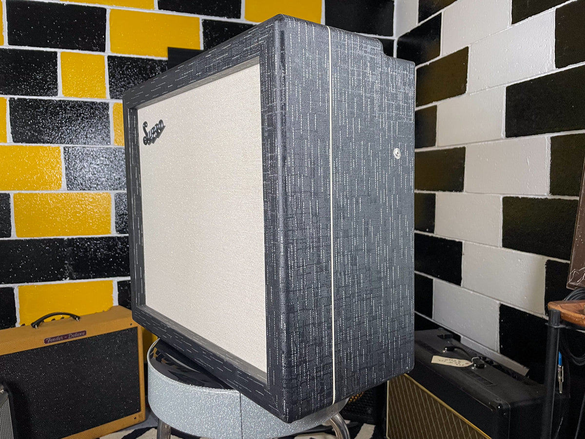 The combo amp is angled, showing its textured dark gray cabinet with a light grille cloth and a single silver knob on the side.