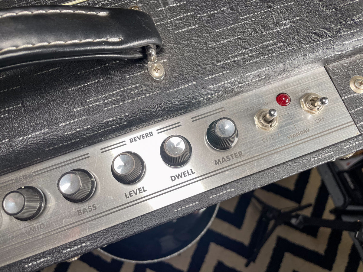 Close-up of the amp's black textured top and brushed metal control panel with six silver knobs, two toggle switches, and a red indicator light.