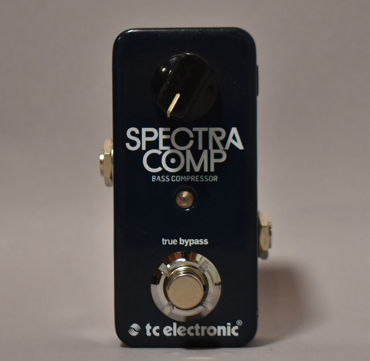 Dark blue pedal with a single black knob, a small gold LED, and a large silver footswitch, viewed from the front.