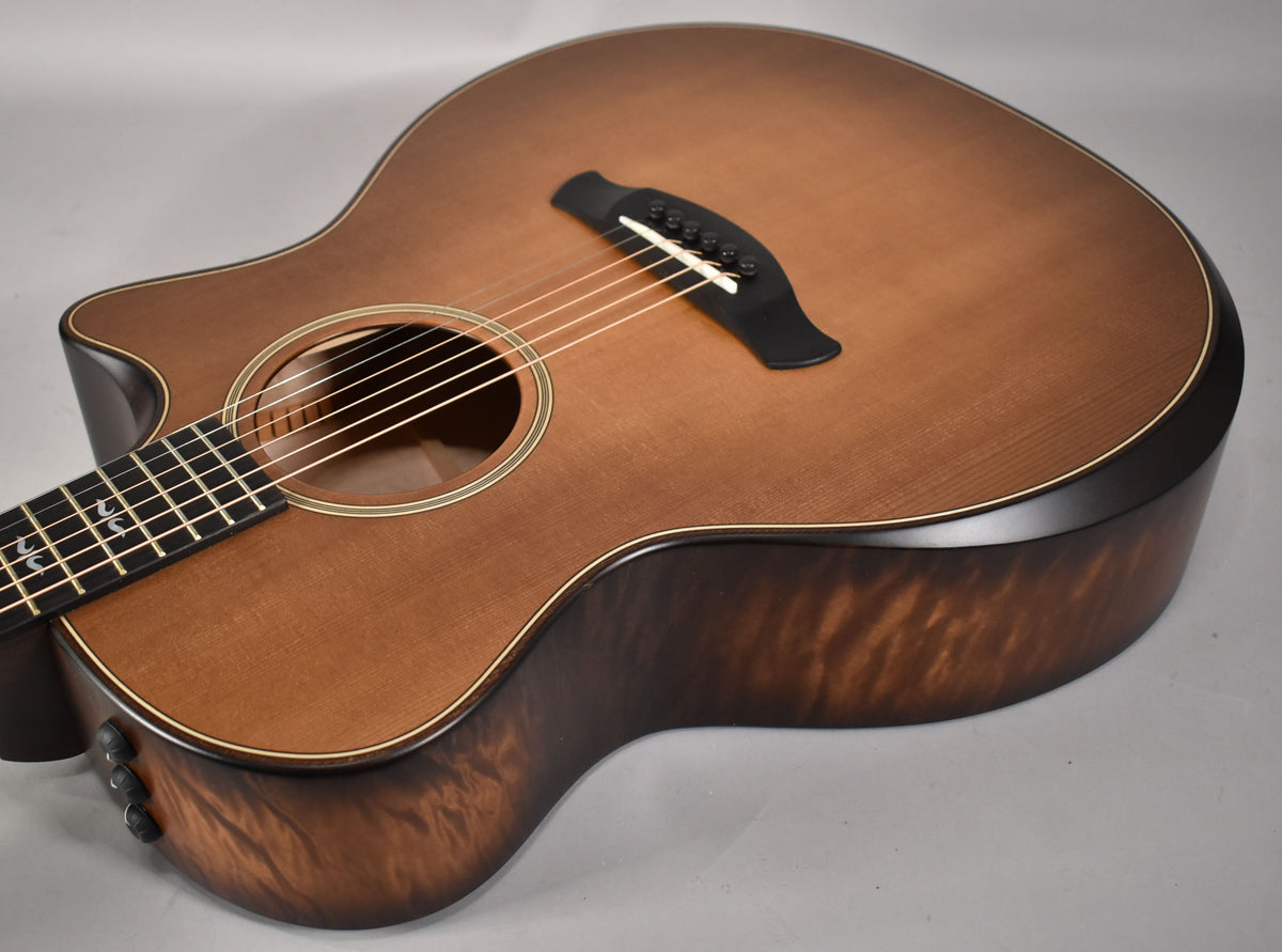 The acoustic guitar's body, with a cutaway, shows a honey burst top and dark, figured sides, angled from the lower bout.