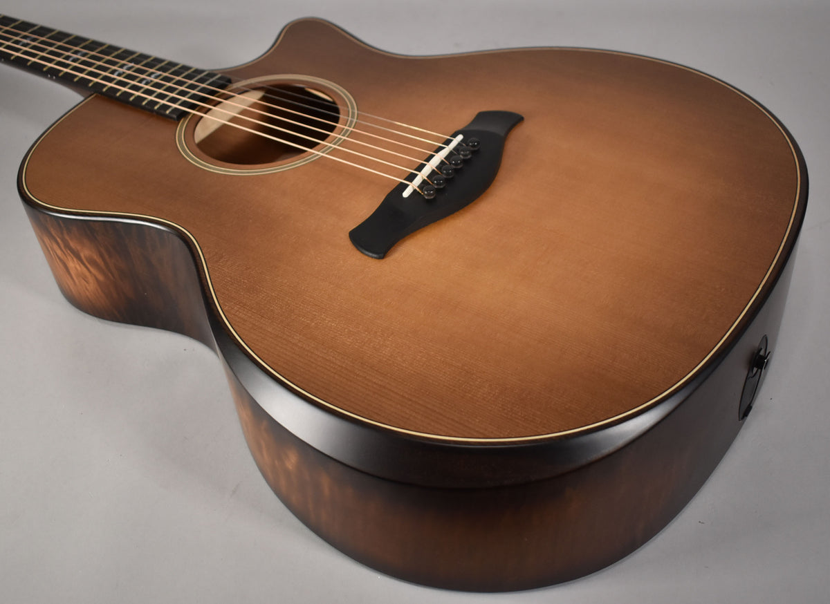 Acoustic guitar body and lower neck, angled from above, showing the Wild Honey Burst finish and dark wood grain on the sides.