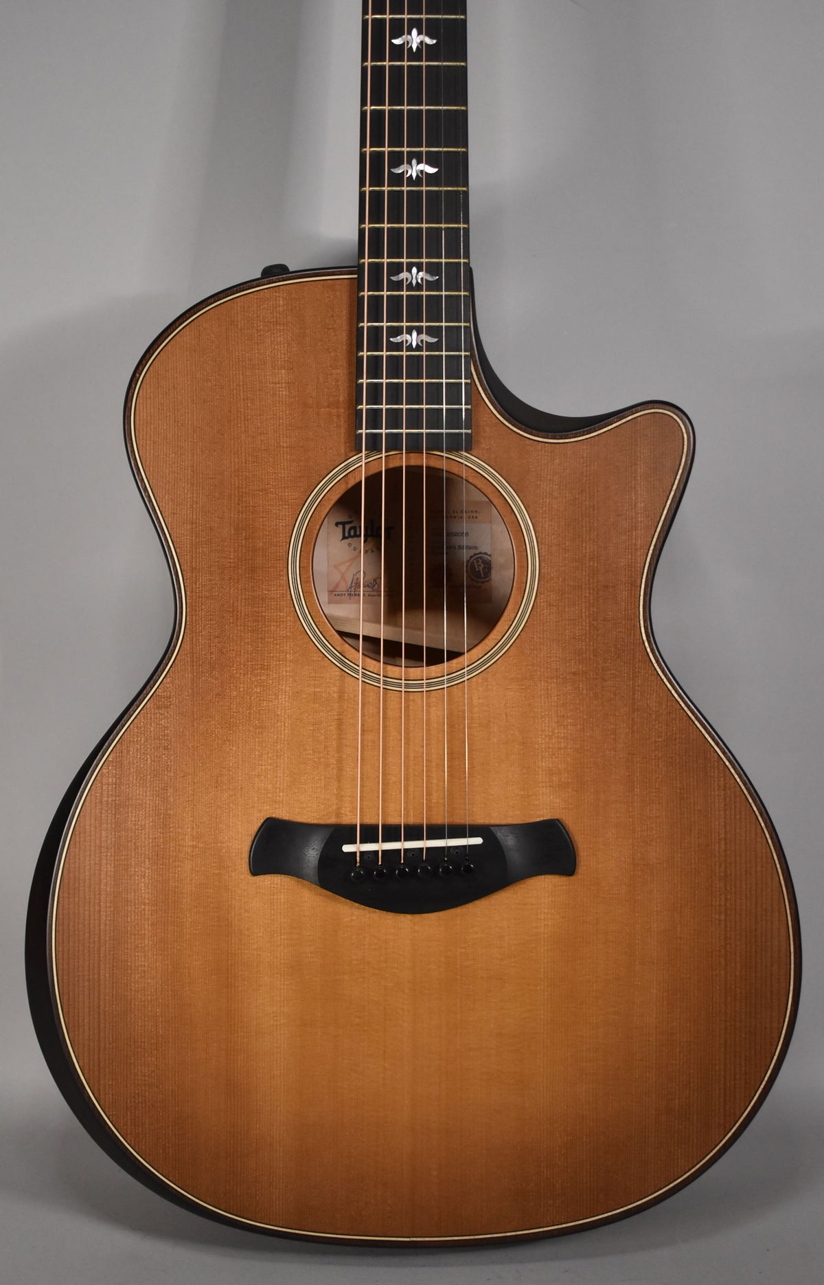 Close-up of the guitar's honey burst body and cutaway, showing the soundhole, black bridge, and ornate fretboard inlays.