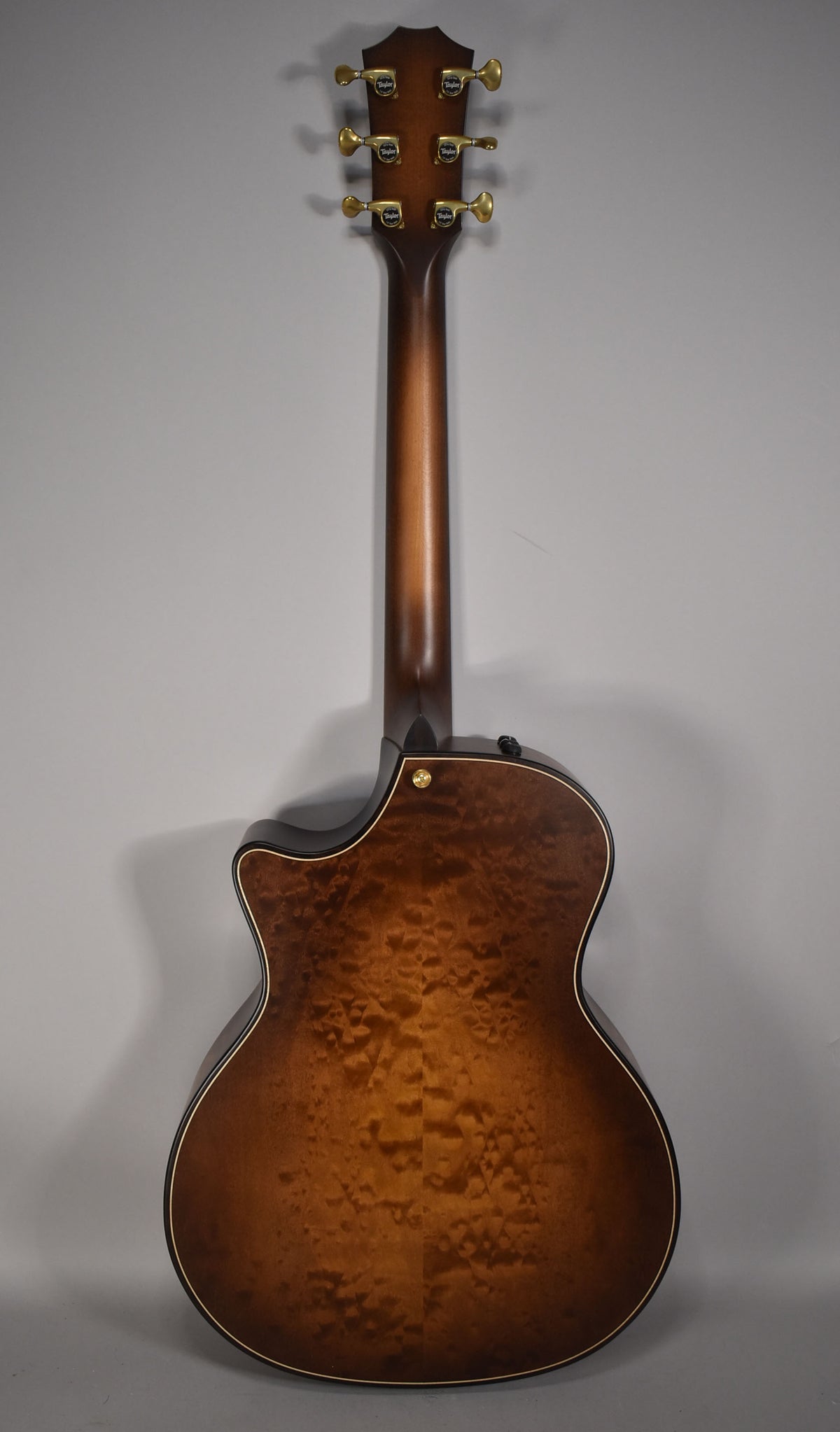The guitar's back and neck are shown, featuring a wild honey burst finish with prominent wood grain and gold tuners.