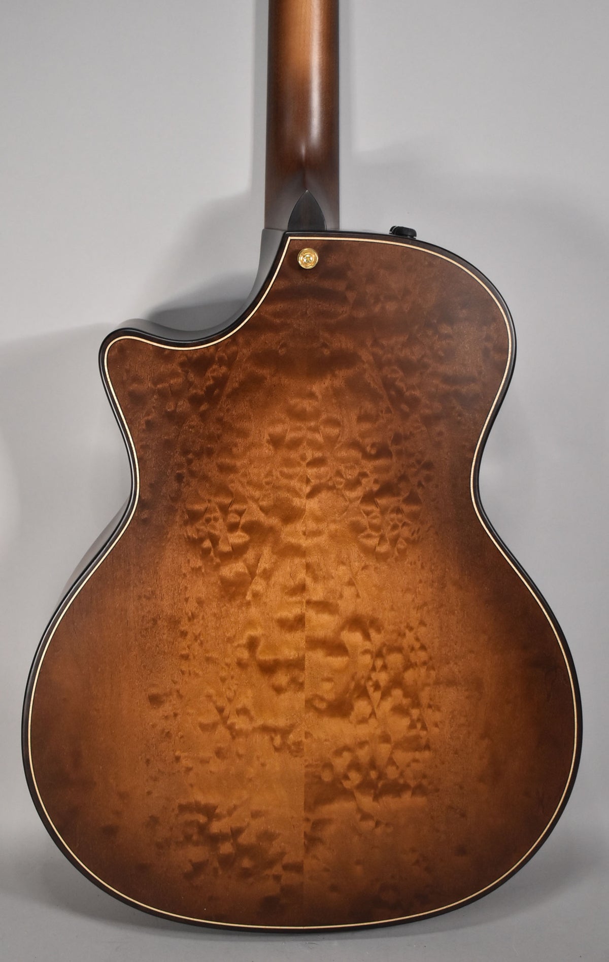 The guitar's back, in a wild honey burst finish with prominent flame maple grain, features a gold strap button.