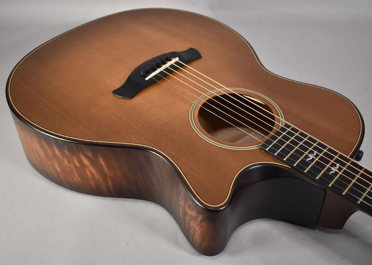 The acoustic guitar's body, cutaway, and lower fretboard are visible, showing a dark honey burst finish with wood grain.