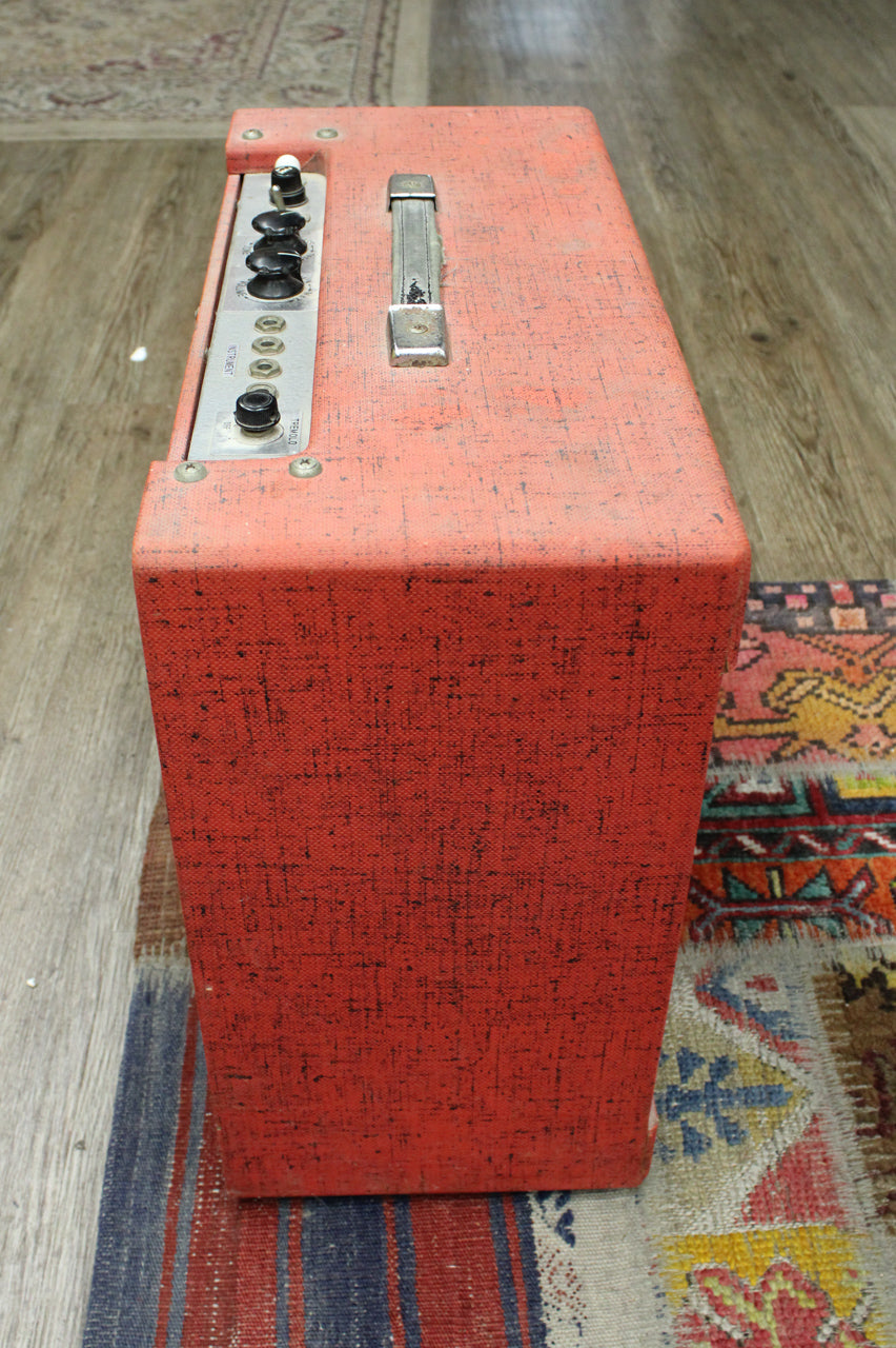 Top-down view of the red and black tolex amp, showing the control panel with black knobs and four input jacks, plus a chrome handle.