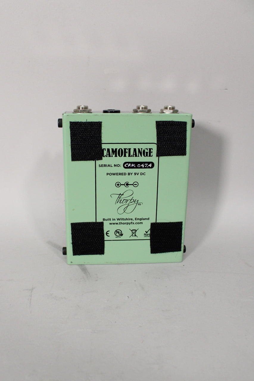 The light green pedal is viewed from the back, showing four black velcro pads and silver input/output jacks.
