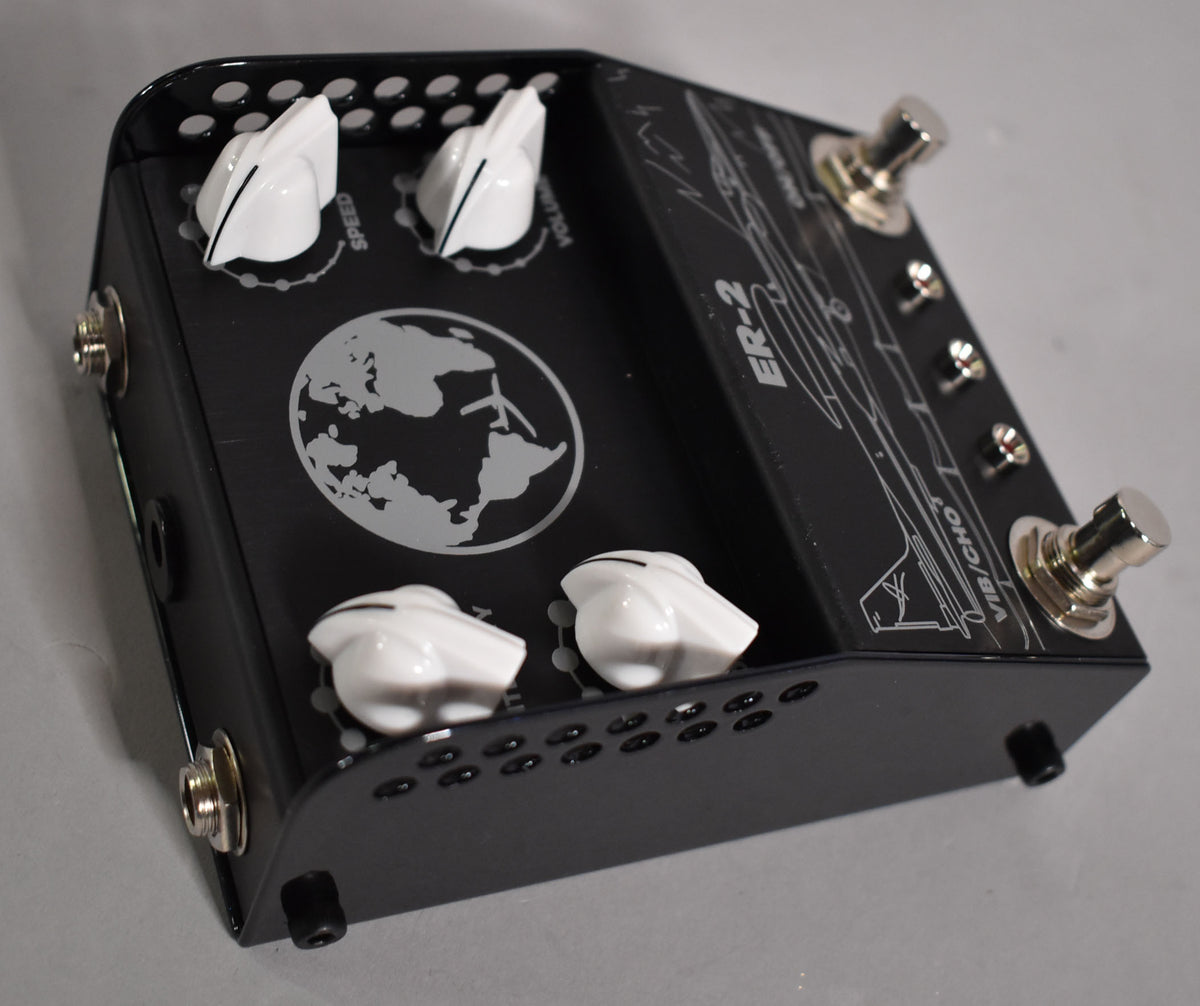 A black guitar pedal with white knobs and silver footswitches, viewed from above at an angle, showing a white globe graphic.