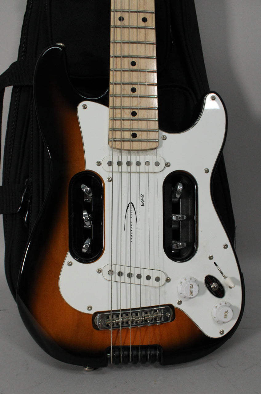 Close-up of a sunburst electric guitar with a white pickguard, showing the maple fretboard, bridge, and controls.
