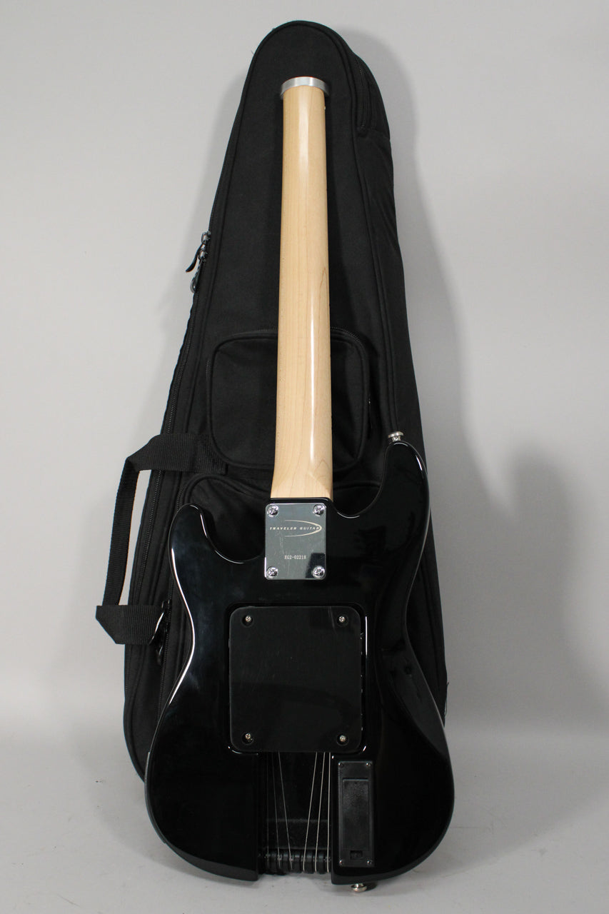 The guitar's glossy black back and light wood neck are visible, with a black gig bag behind it.