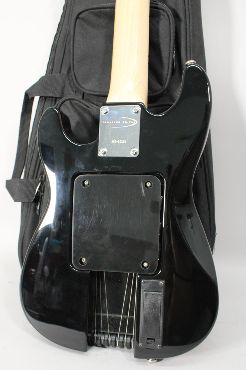 Rear view of the black electric guitar, showing the neck plate, control cavity cover, and battery compartment.