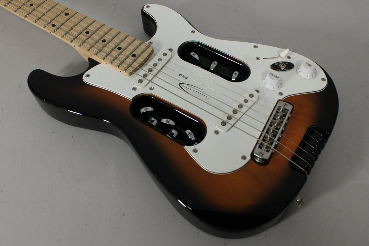 Sunburst electric guitar, angled from above, showing the body, white pickguard, two large cutouts, and maple fretboard.