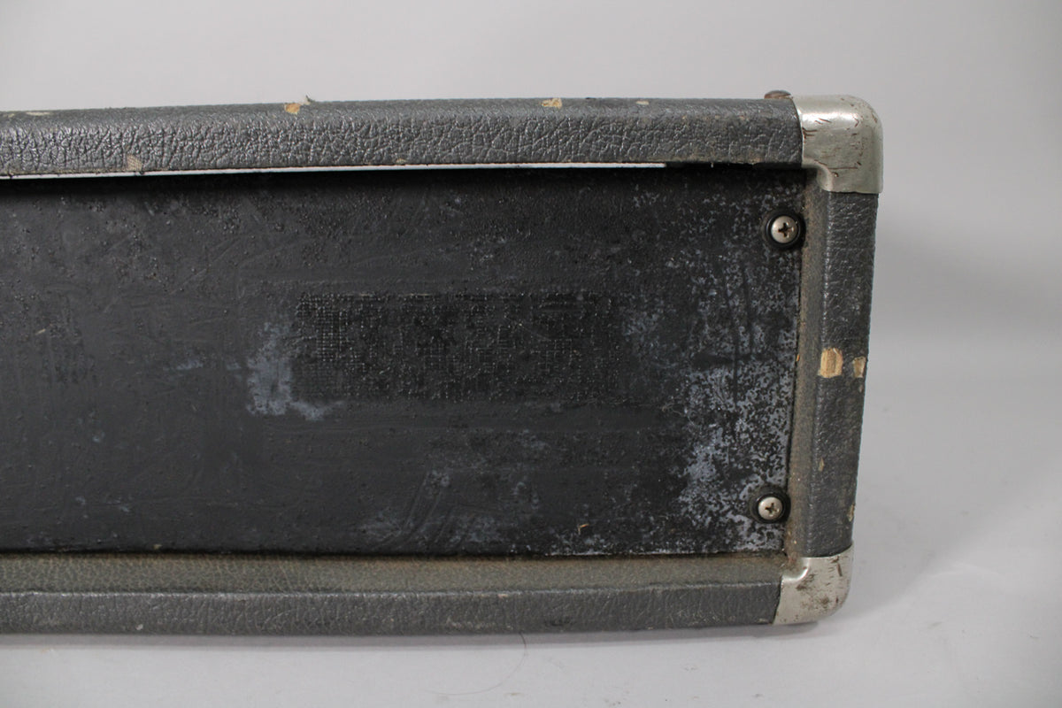 Top-down view of the amp's black textured top and right side, showing scuffs, worn metal corner protectors, and two screws.