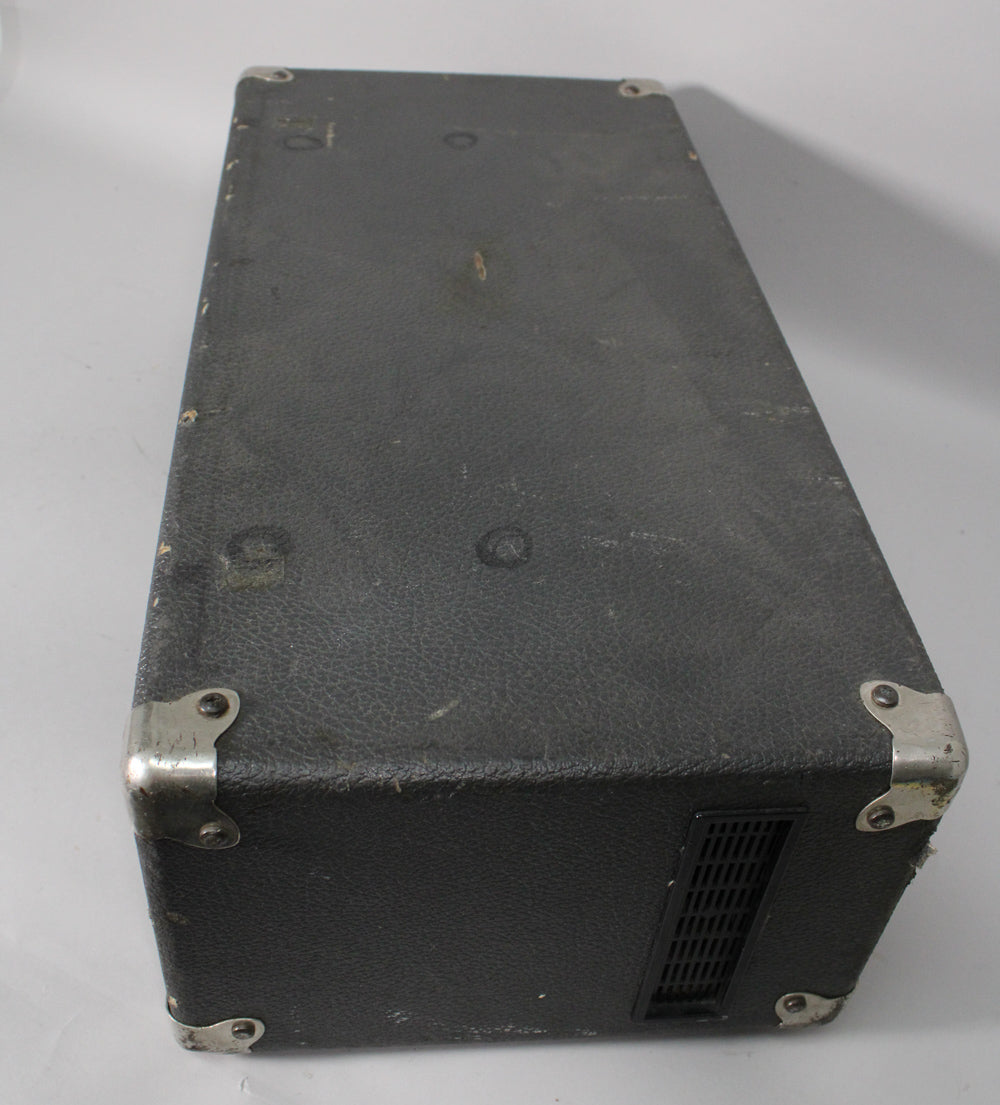 Top-down view of the dark grey, textured amplifier, showing its worn surface, metal corner protectors, and a side vent.