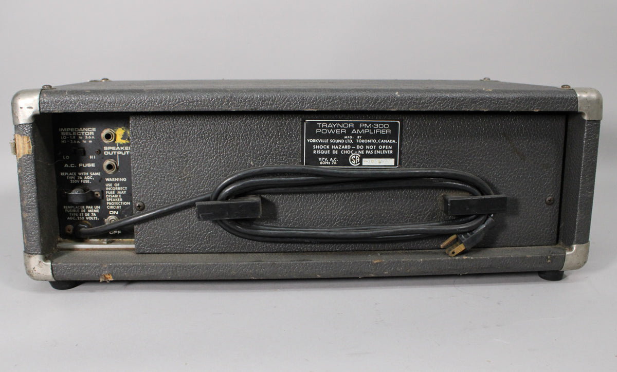 Rear view of a dark gray amplifier with a textured finish, showing the power cord wrapped around a hook and some wear on the corners.