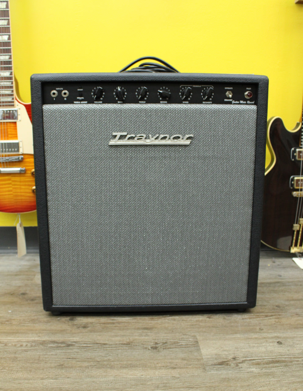 Front view of a black combo amp with a silver grille, black control panel, and nine black knobs.