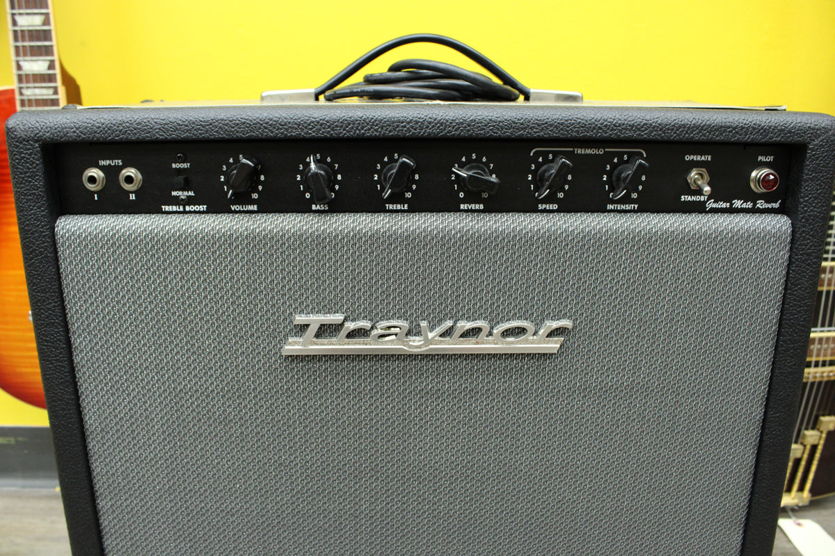 Front view of a black textured amp with a gray grille cloth, silver control panel, black knobs, and a red pilot light.