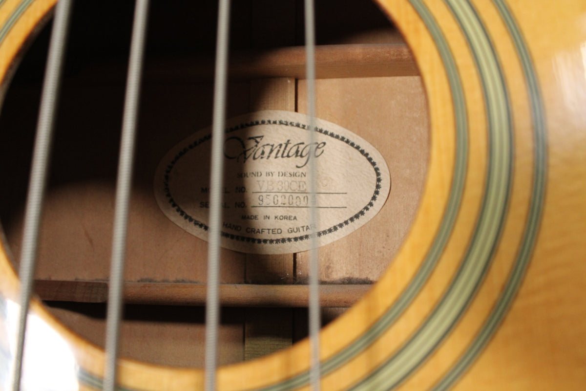 Close-up of the soundhole, showing the light wood interior and a paper label with text, partially obscured by four strings.