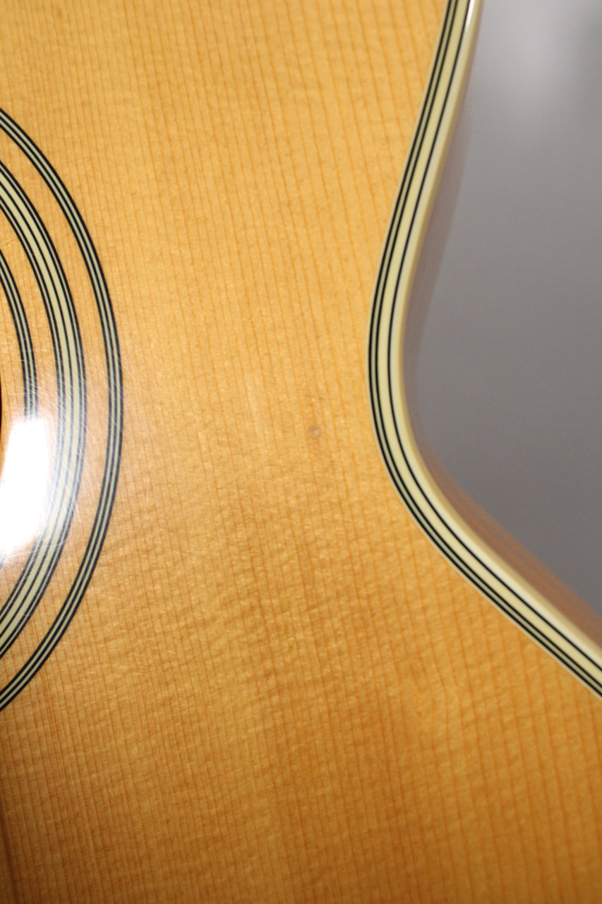 Close-up of the natural wood body, showing the soundhole rosette and cutaway binding, with a small ding near the center.