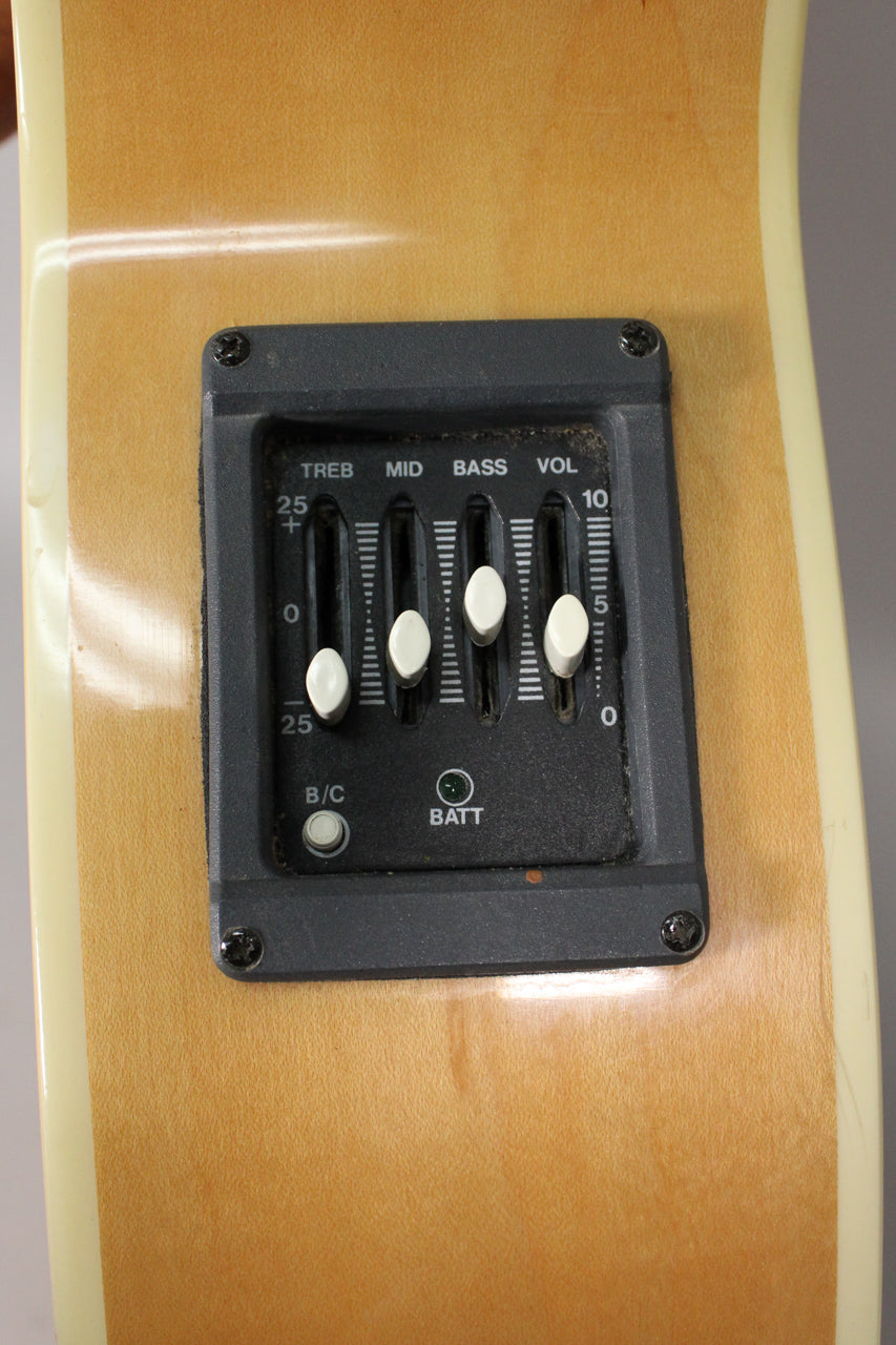 Close-up of the natural finish body, showing the black preamp with four white slider controls and two round buttons.