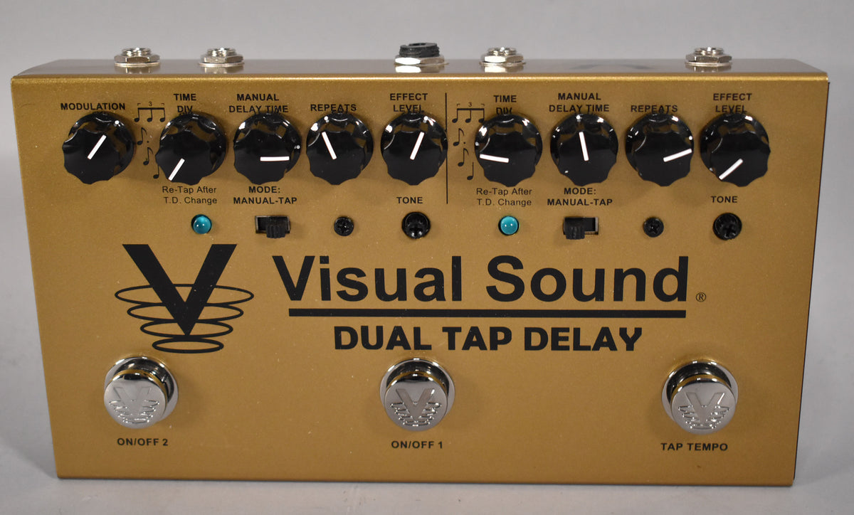 A gold-finished pedal, viewed from above, with nine black control knobs, two toggle switches, three chrome footswitches, and two blue LEDs.