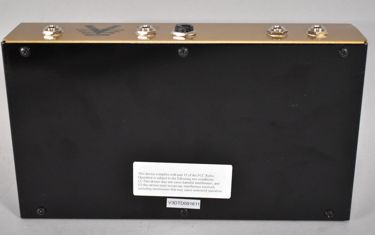 The pedal's black underside is visible, with a gold top edge showing five input jacks and a black power input.
