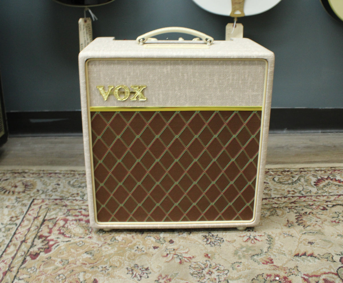 Front view of a fawn-colored combo amp with a brown diamond-patterned grille, gold piping, and a cream handle.