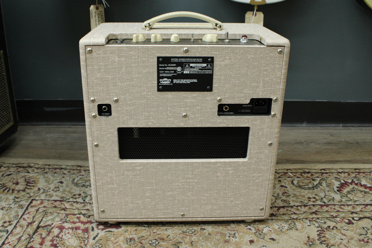 Rear view of the fawn-colored combo amp, showing a black metal control panel, a cream handle, and a rectangular vent.