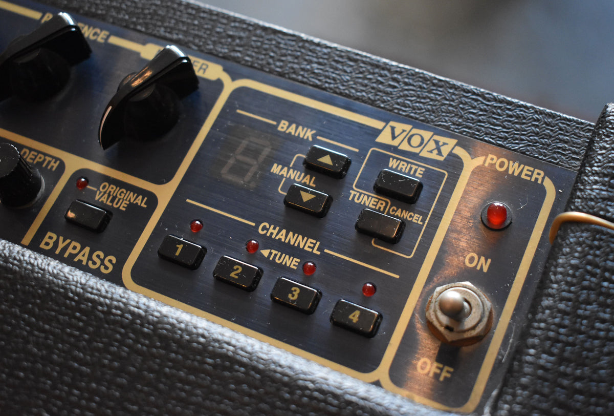 Close-up of the dark blue control panel with gold lettering, showing black buttons, red indicator lights, and a metal toggle switch.
