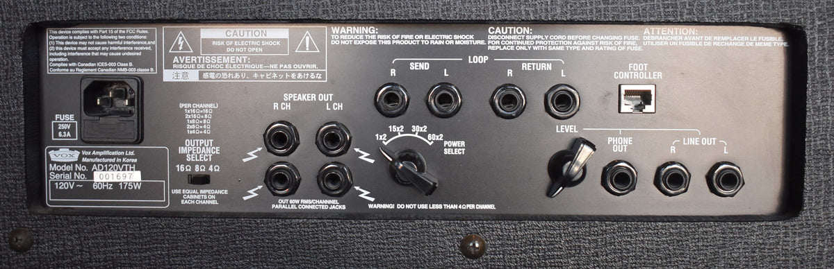 The amp's black rear panel, covered in white text, shows various inputs, outputs, and two black rotary knobs.