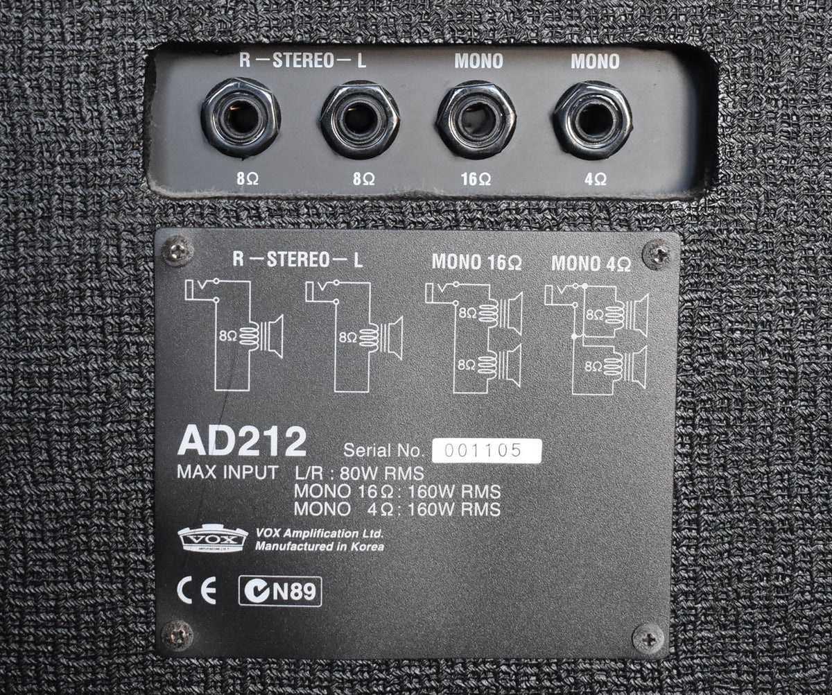 Close-up of the black textured rear panel with four input jacks and a metal plate detailing wiring diagrams and specifications.