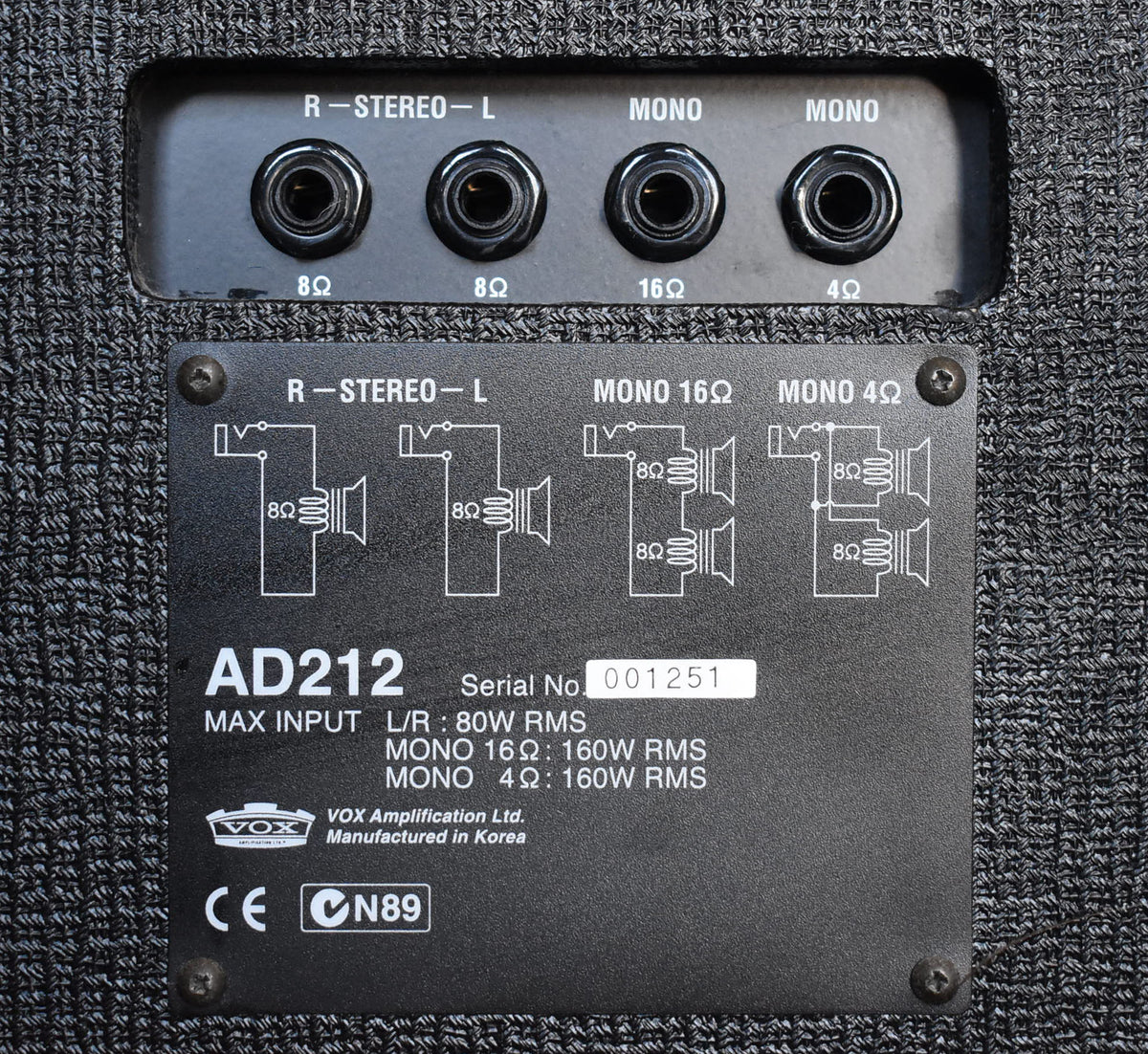 Close-up of the black metal input panel with four 1/4" jacks and a data plate, set into a dark gray textured cabinet.
