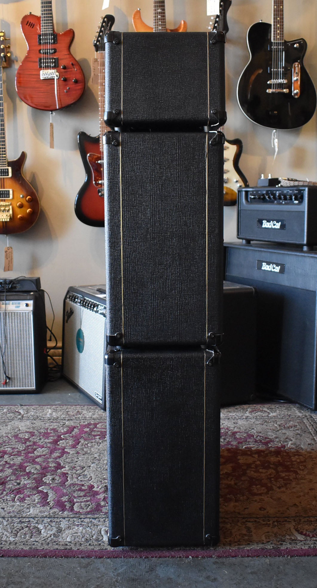 The black textured amplifier head sits atop two matching cabinets, forming a tall stack with gold piping and metal corner protectors.