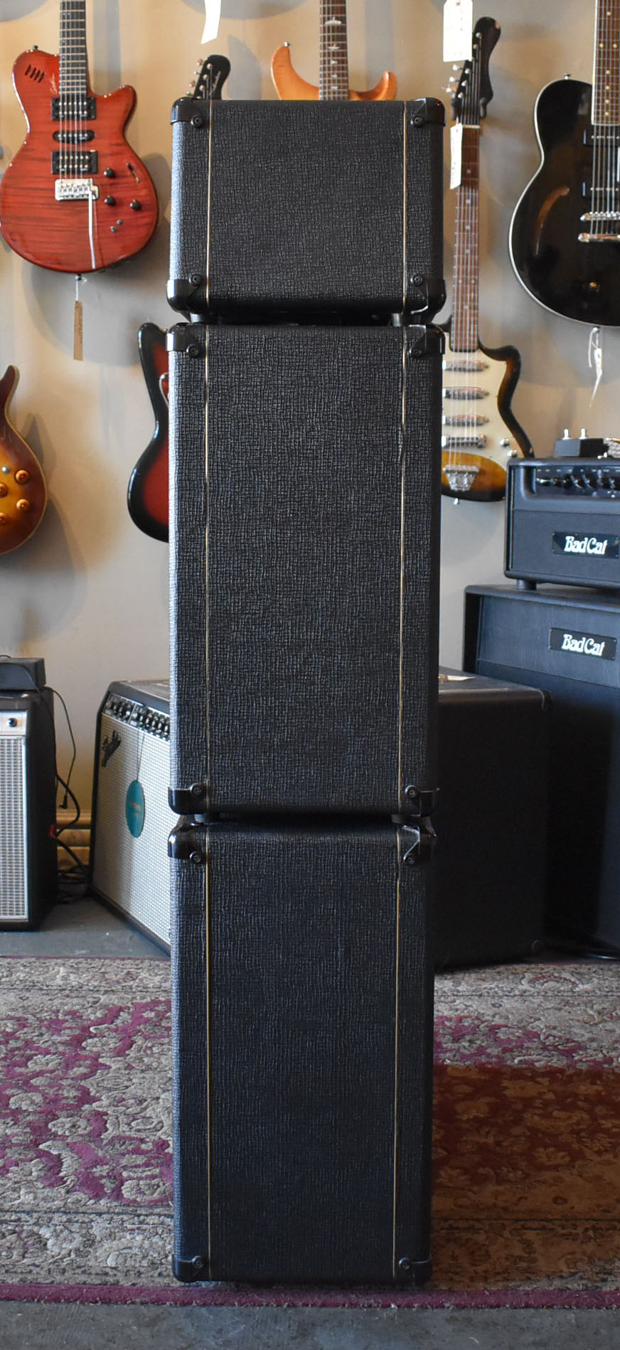 Full-height front view of the black textured amp head and two cabinets, stacked vertically, with gold piping and corner protectors.