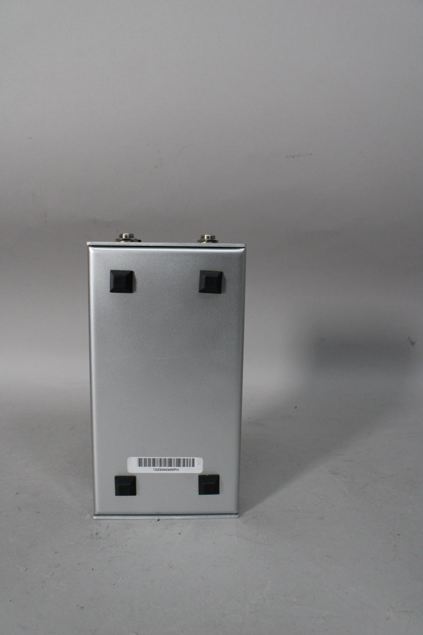 The silver pedal is viewed from the back, showing two input jacks, four black rubber feet, and a barcode sticker.
