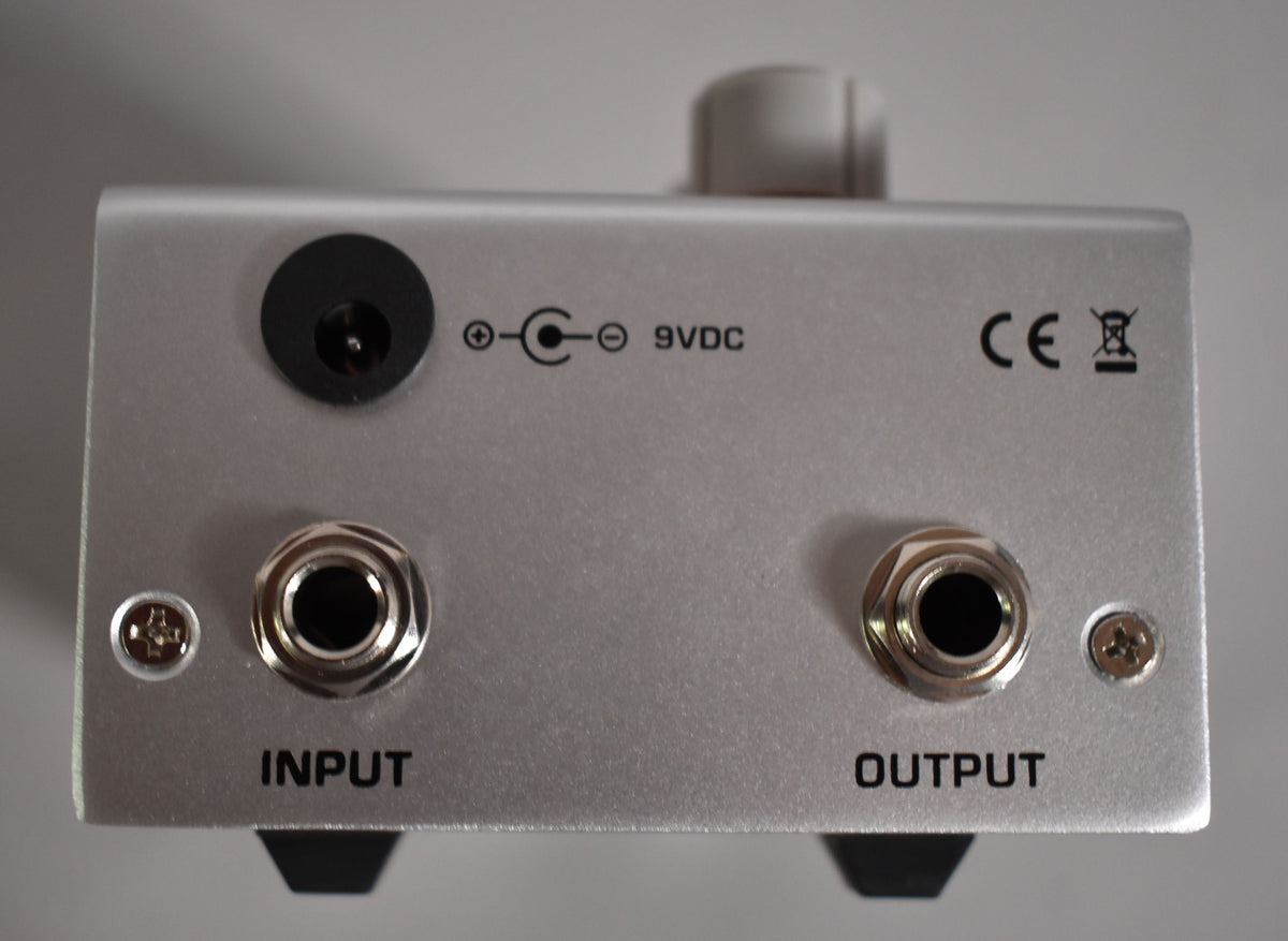 The pedal's silver rear panel shows a 9VDC power input, input and output jacks, and two small screws.