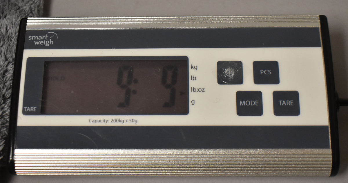 A close-up of a digital scale displaying "9.9" in large black digits, with "lb" selected as the unit.