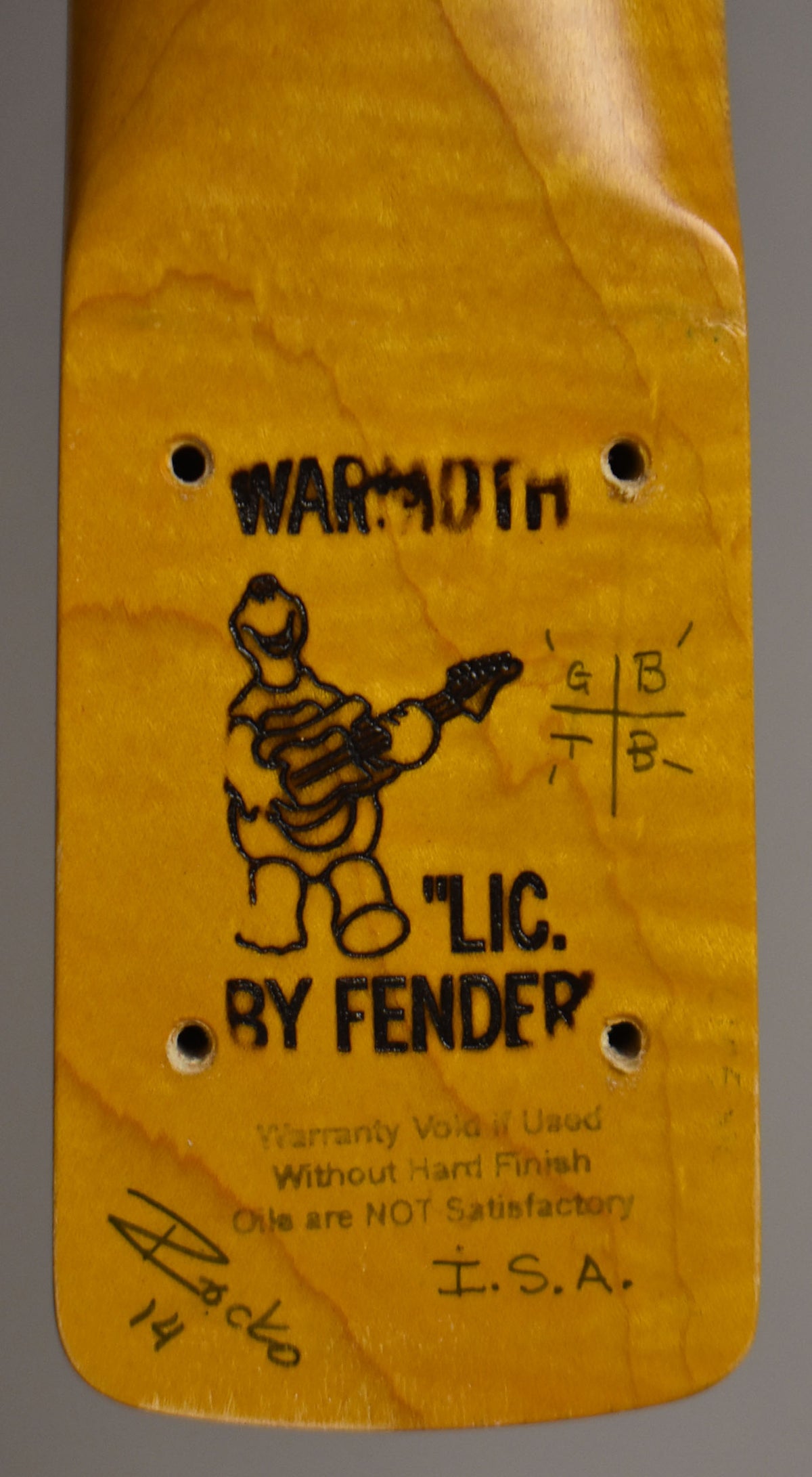 Close-up of a light brown wooden neck heel with four screw holes and a dark wood-burned logo.