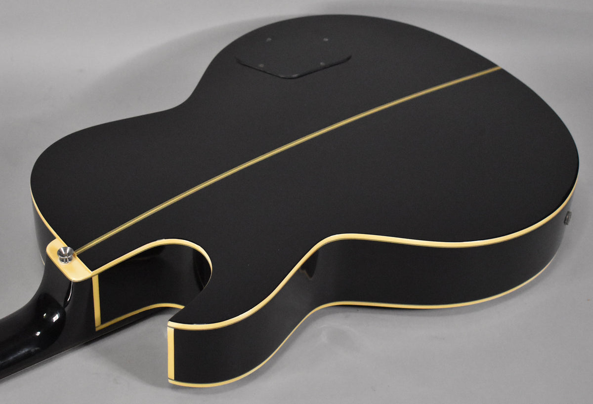 The bass's matte black back and sides are visible, with cream binding and a single cream stripe down the center.