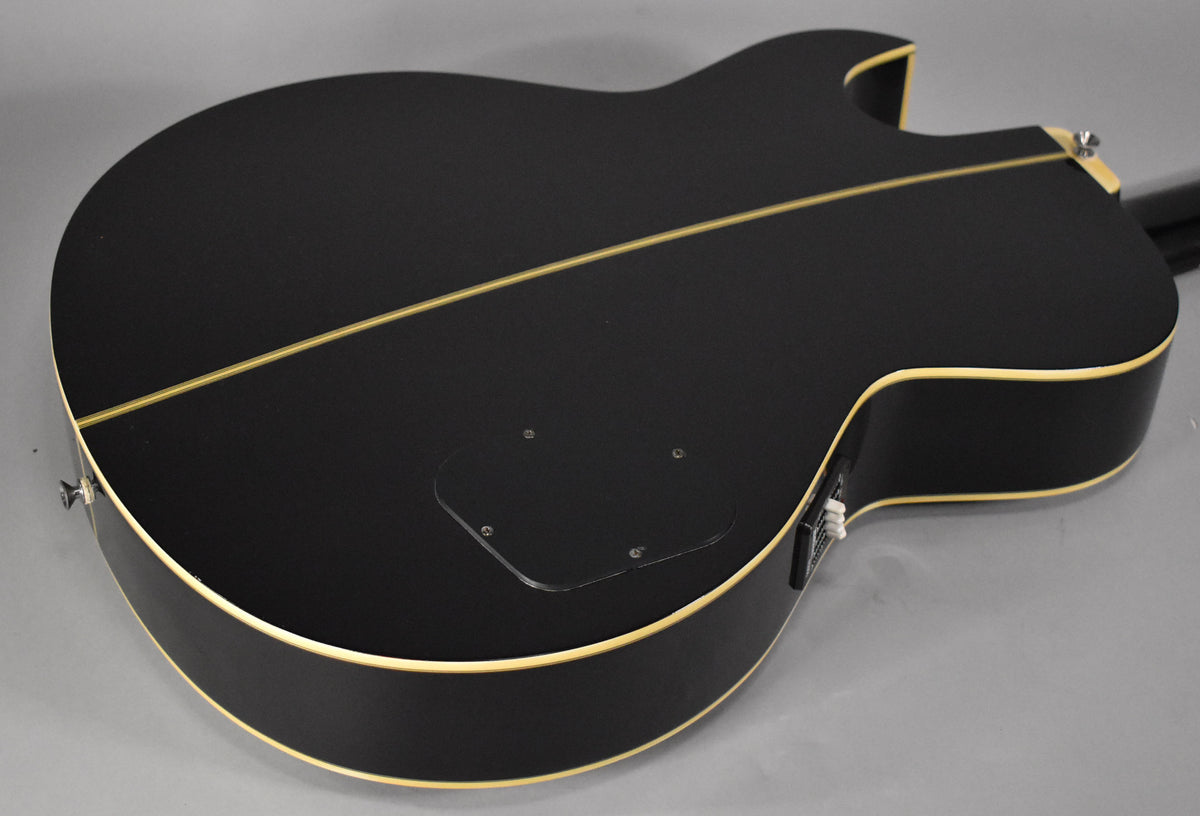 The bass's black matte back and sides are visible, with cream binding, a clear control plate, and a thin center seam.