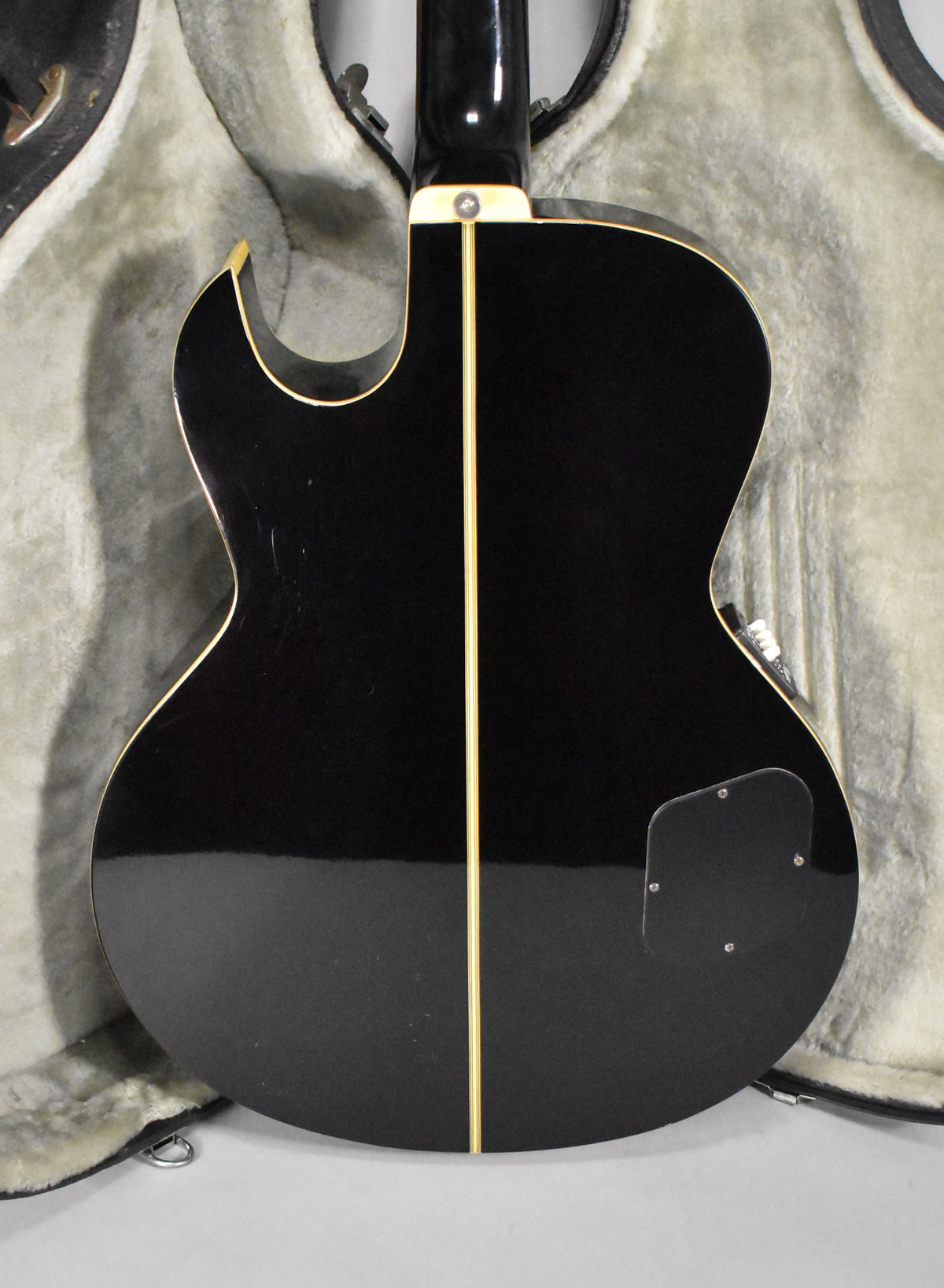 Rear view of a black hollowbody bass with a glossy finish, cream binding, and a vertical cream stripe down the center.