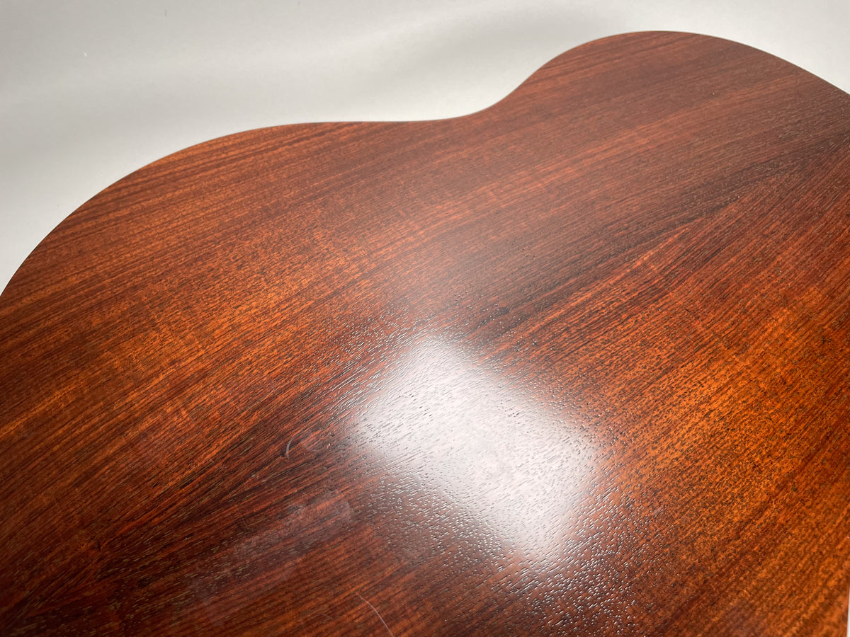 Close-up of the guitar's dark reddish-brown back, showing wood grain and a few light scratches on the glossy finish.