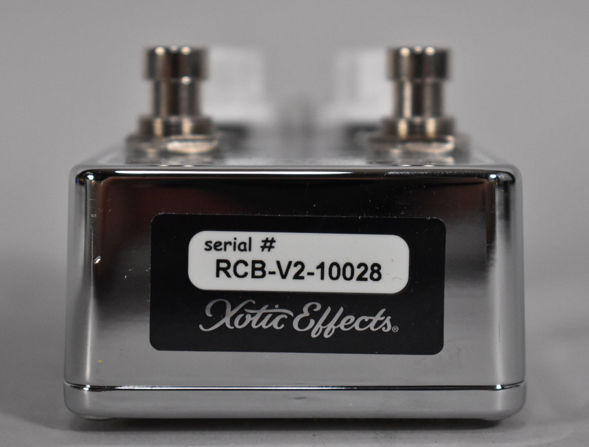 Close-up of a chrome Xotic Effects pedal with serial # RCB-V2-10028 on a black and white label.