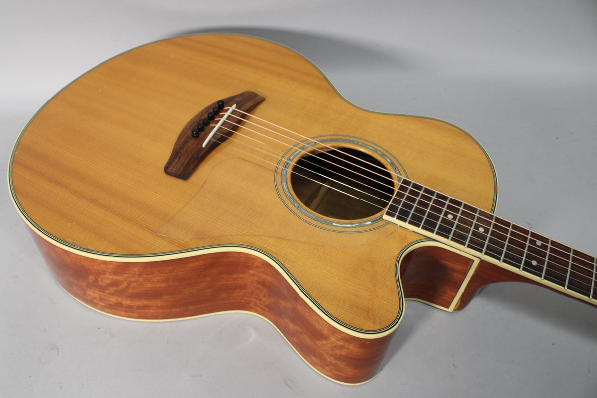 Acoustic guitar with a natural finish, light wood top, dark wood sides, and a cutaway body, viewed from above.