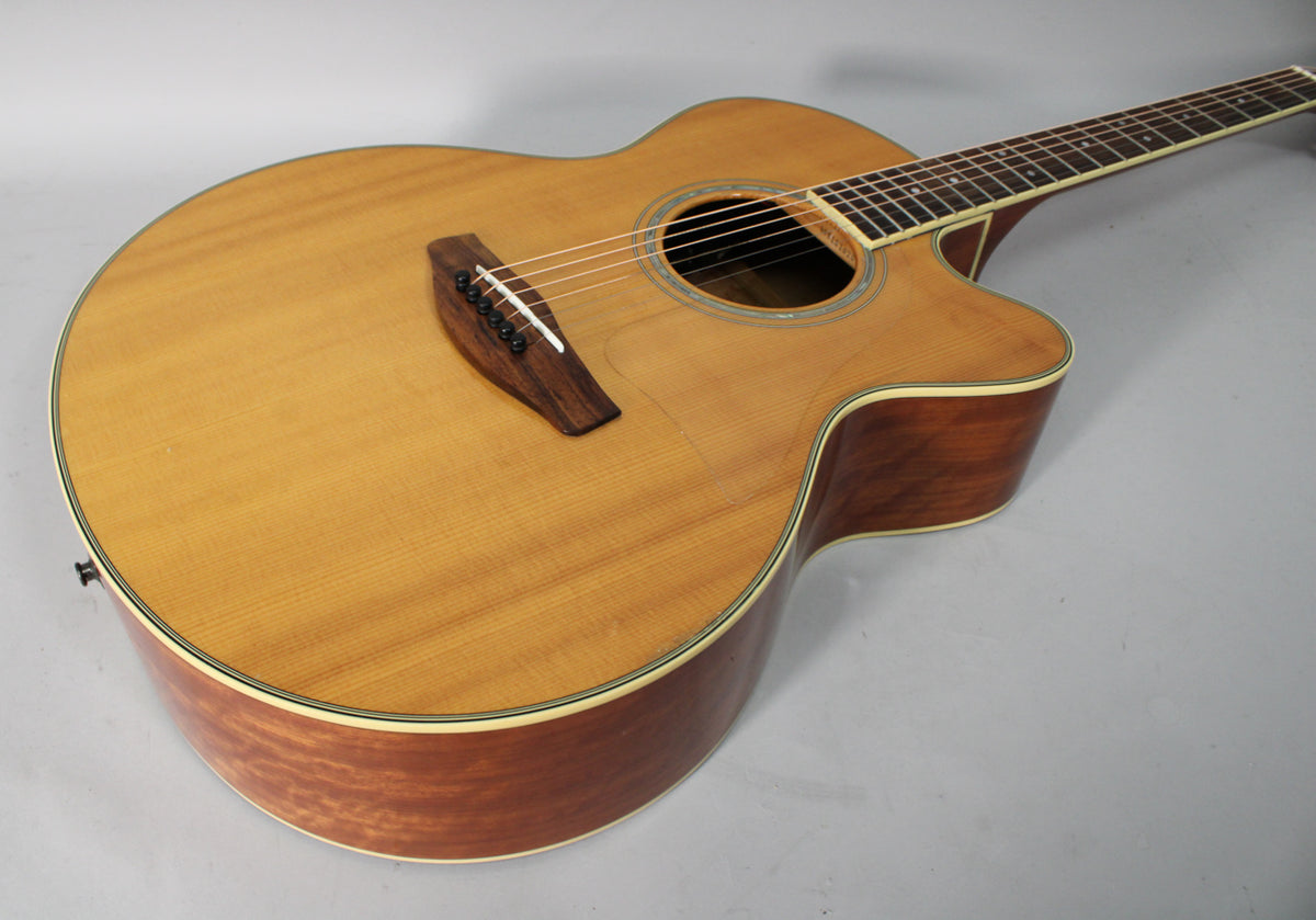 The acoustic-electric guitar is angled, showing its light-wood top, dark-wood sides, cutaway, and soundhole with a decorative rosette.