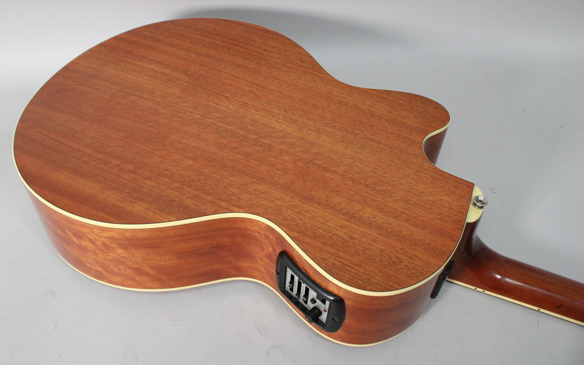 The back of a light brown acoustic-electric guitar with a cutaway, showing the preamp controls and part of the neck.
