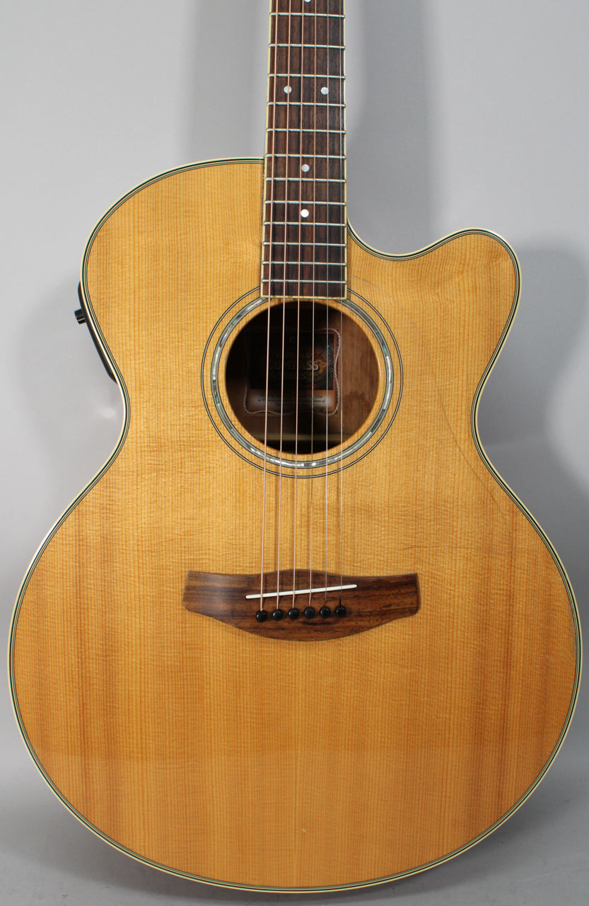 Full-frame view of the natural finish acoustic guitar, showing the cutaway body, soundhole with abalone rosette, and dark wood bridge.